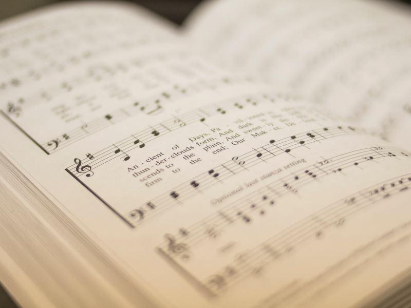 A book of sheet music opens to a page with notes and lyrics.