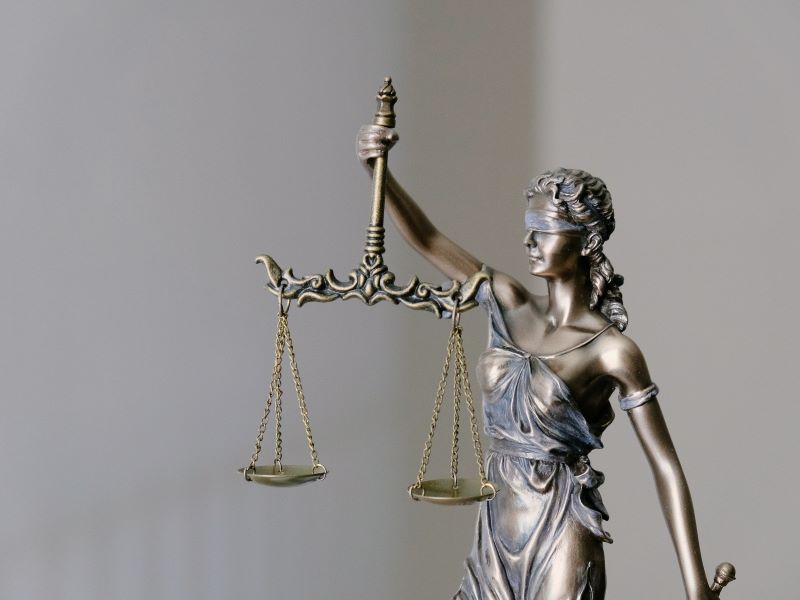 A small statue of the personified Justice stands blindfolded, holding aloft a set of scales.