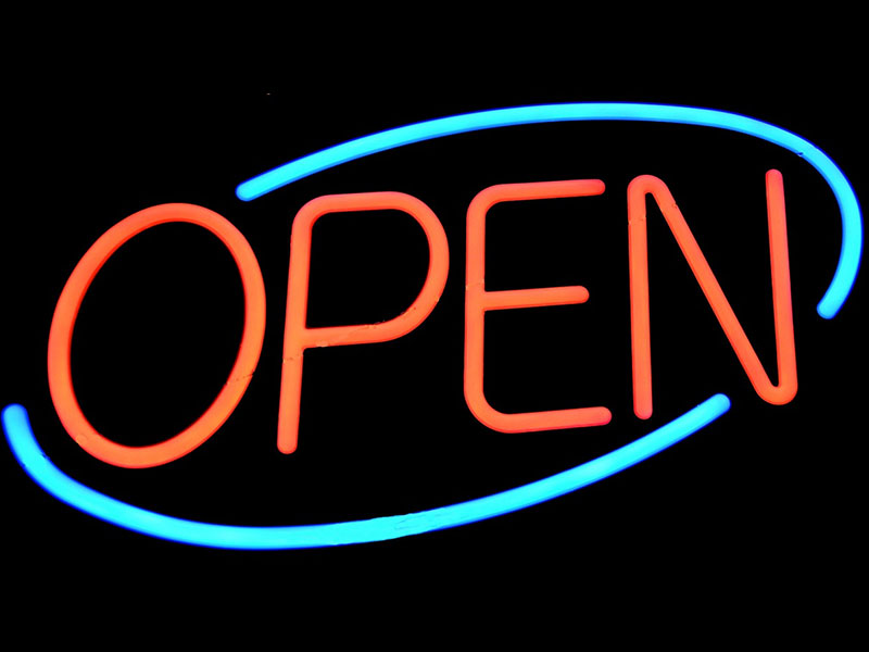 An open-for-business sign with neon red letters spelling “OPEN” inside a neon blue oval.