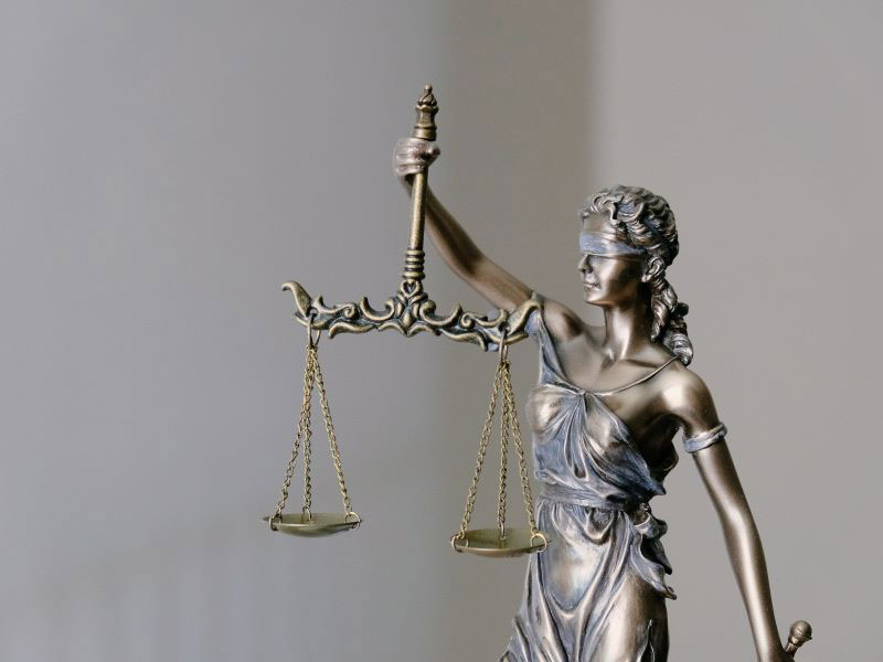 A small statue of Justice—personified as a woman wearing a blindfold and holding aloft a set of scales—symbolizing fair and equal treatment under the law. 